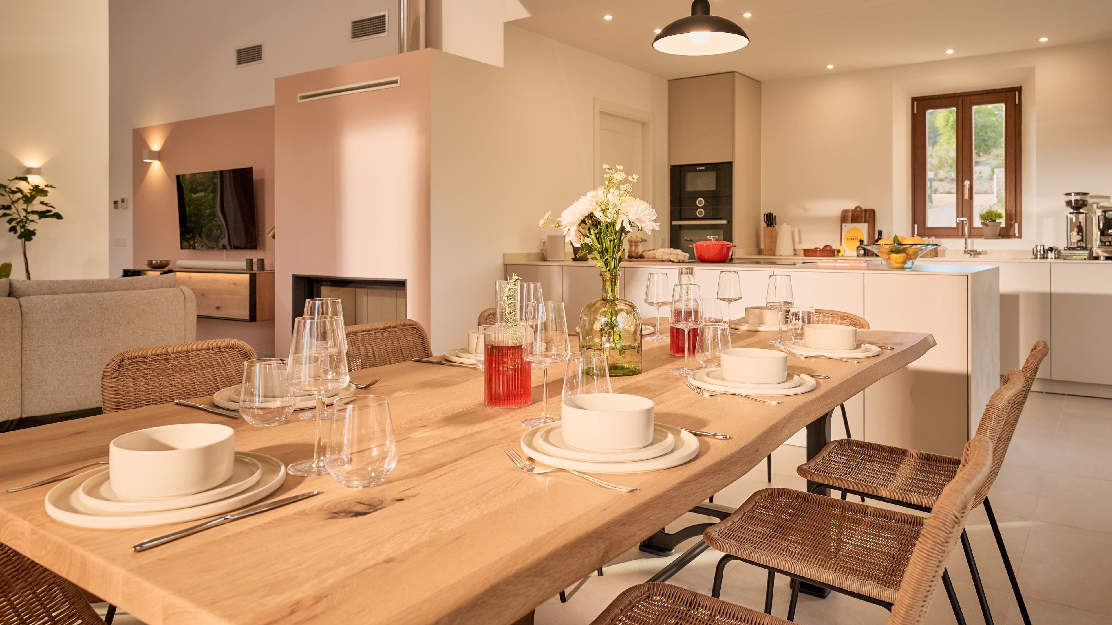 Blick auf den gedeckten Esstisch im Traumhaus auf Mallorca bestehend aus einem großen hellen Holztisch und 8 hellen Rattanstühlen.